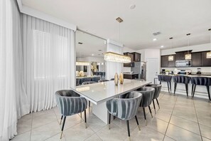 Welcome to this chic dining area with a marble table and plush velvet chairs for your comfort. Enjoy the warm ambiance created by soft natural light filtering through elegant sheer curtains, making it ideal for gatherings. - 6BR house sleeps 16 with private pool (Davenport)