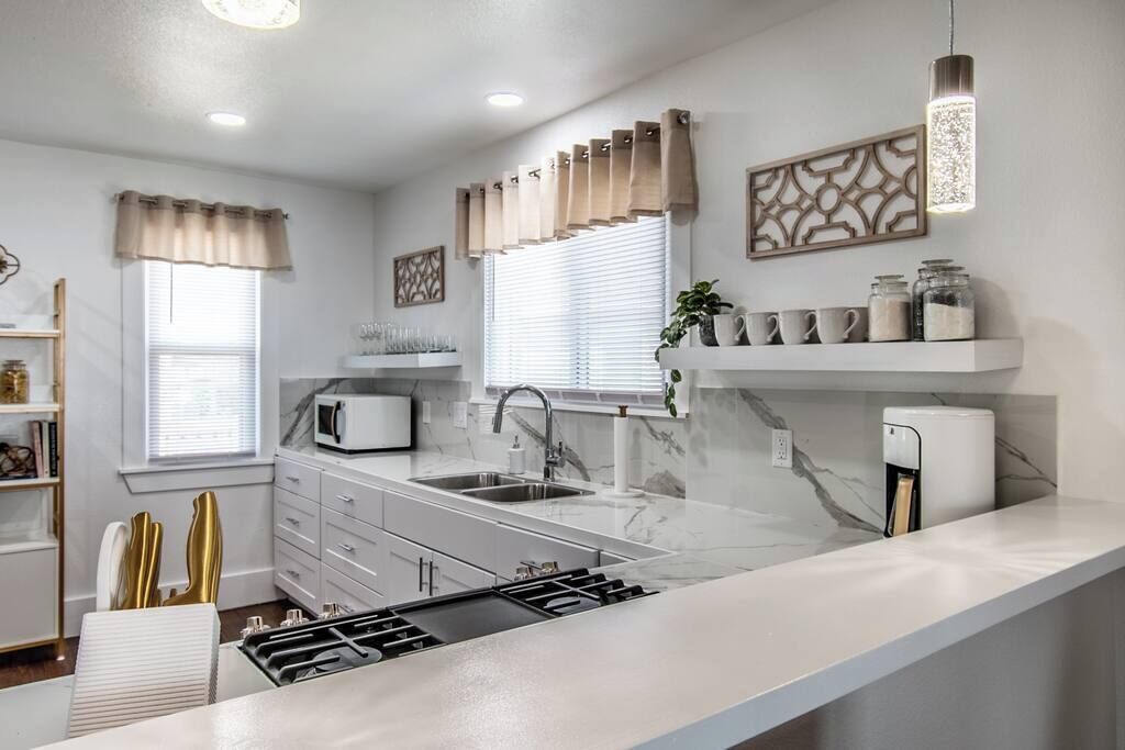A modern kitchen with a central island, a built-in microwave, and a coffee machine.