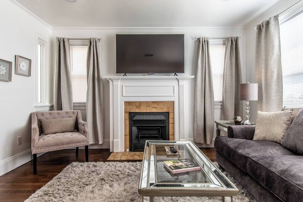 A living room with a fireplace, a television, a sofa, and a chair.