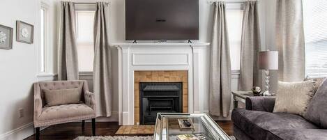 A living room with a fireplace, a television, a sofa, and a chair.
