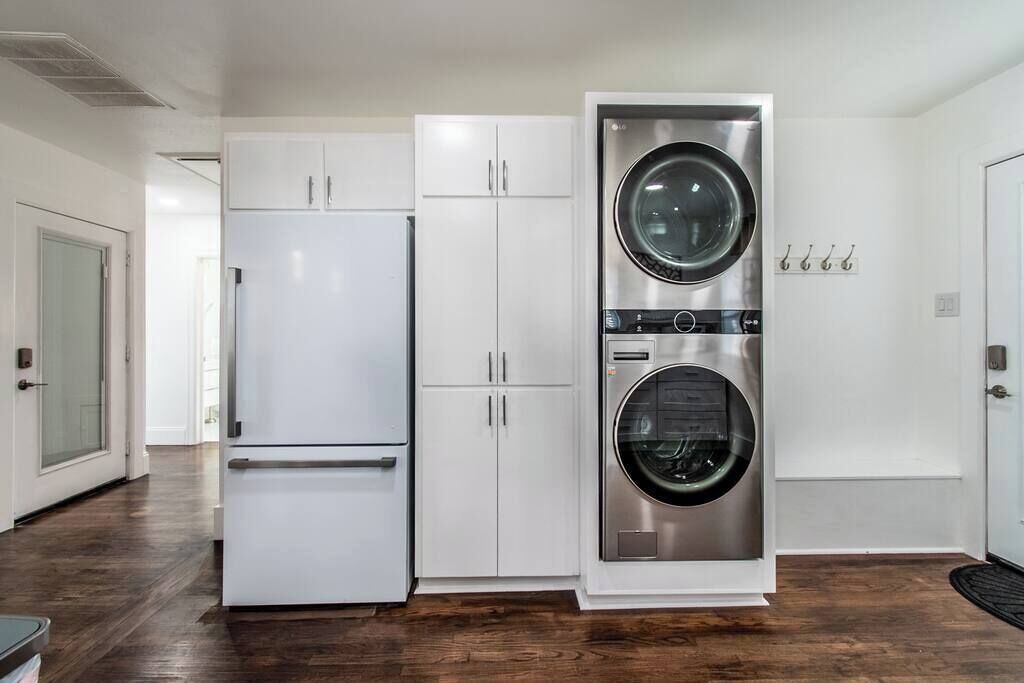 A compact kitchen with a white refrigerator, a double-door oven, and a stainless steel washer and dryer unit.