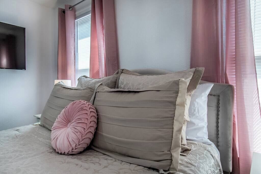 A bedroom with a bed, pillows, and curtains.