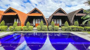 Una piscina con reflejos, rodeada de edificios con techos abovedados y vegetación.
