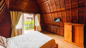 Una habitación con una cama, un televisor montado en la pared y un armario de madera.