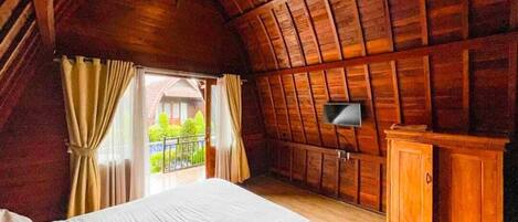 A room with a bed, a TV mounted on the wall, and a wooden cabinet.