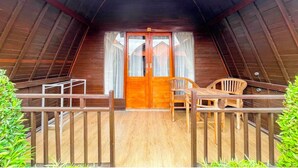 Una habitación estilo ático con una puerta de madera, dos sillas de madera y una mesa pequeña.