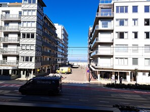 Ein mehrstöckiges Gebäude mit Balkonen, ein gelber Transporter und ein strahlend blauer Himmel.