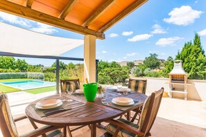 An outdoor dining area with a pool, a barbecue grill, and a view of the surrounding landscape. - Country House 'Calderitx' with Private Pool, Wi-Fi and Air Conditioning (Ariany)