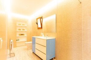 A bathroom with a white sink, a mirror, a toilet, and a shelf with toiletries. - Country House 'Calderitx' with Private Pool, Wi-Fi and Air Conditioning (Ariany)