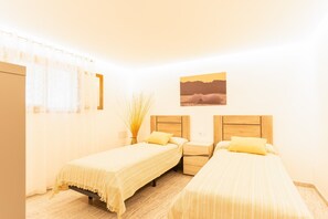 A room with two beds, a nightstand, a vase with dried plants, and a painting on the wall. - Country House 'Calderitx' with Private Pool, Wi-Fi and Air Conditioning (Ariany)