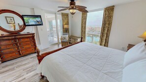 Ein Hotelzimmer mit Bett, einem Holzschrank, einem Fernseher, einem Deckenventilator und Blick auf die Stadt.