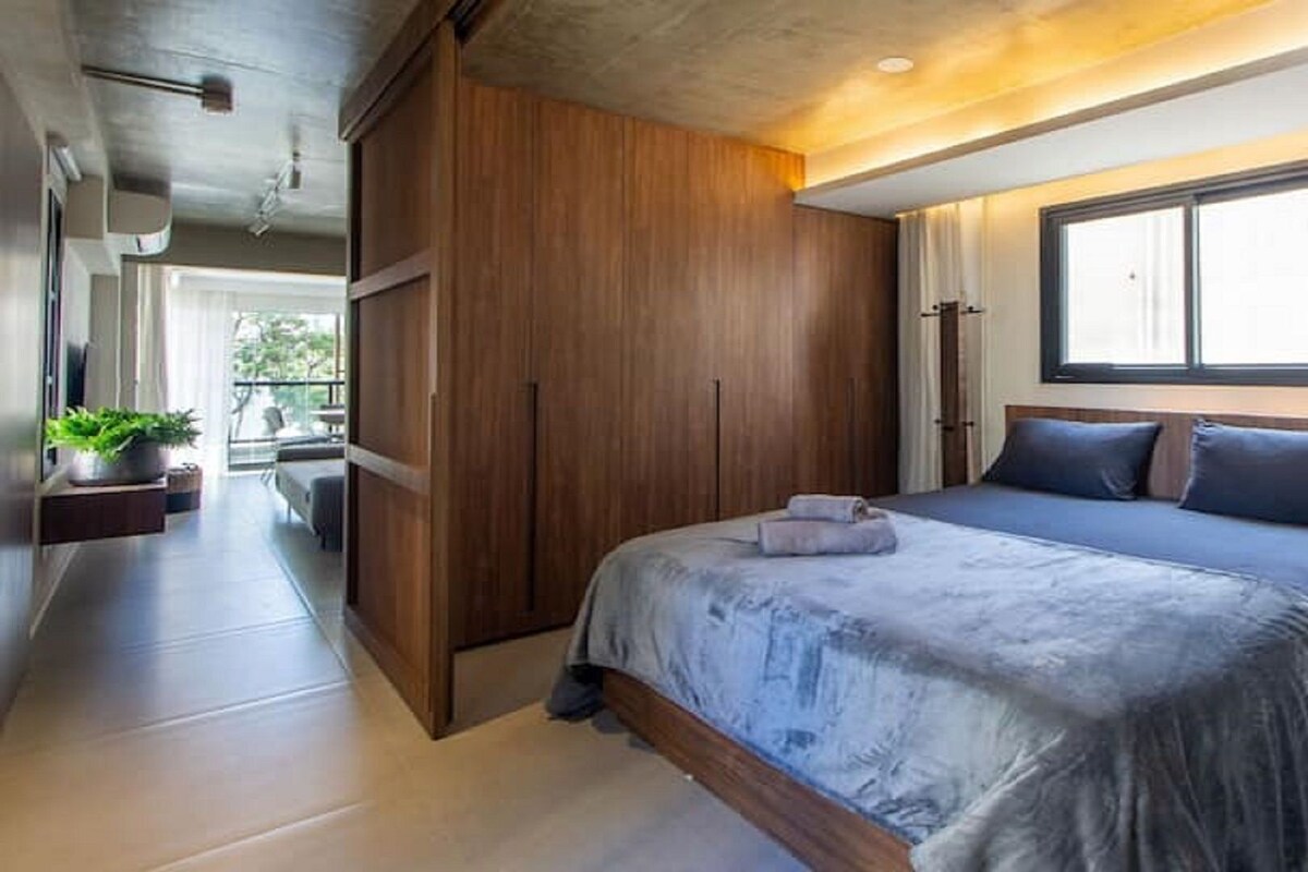 A bedroom with a large bed, wooden wardrobe, and a window with curtains.
