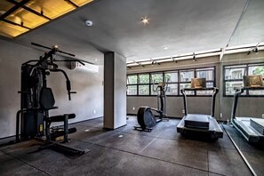 A gym with exercise equipment, large windows, and a concrete floor. - Arte Itaim (São Paulo)