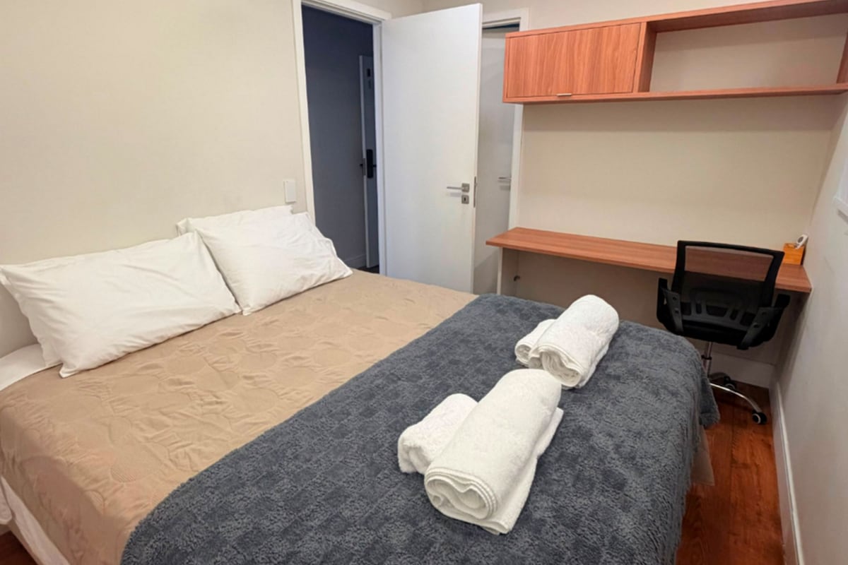 Ein Hotelzimmer mit einem Bett, einem Deckenventilator, einem Holztisch und einem Stuhl.