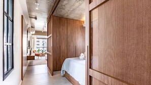 A hotel room with a bed, a wooden wardrobe, a window, and a view of the outside. - Arte Itaim (São Paulo)