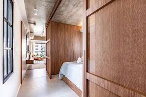 A hotel room with a bed, a wooden wardrobe, a window, and a view of the outside. - Arte Itaim (São Paulo)