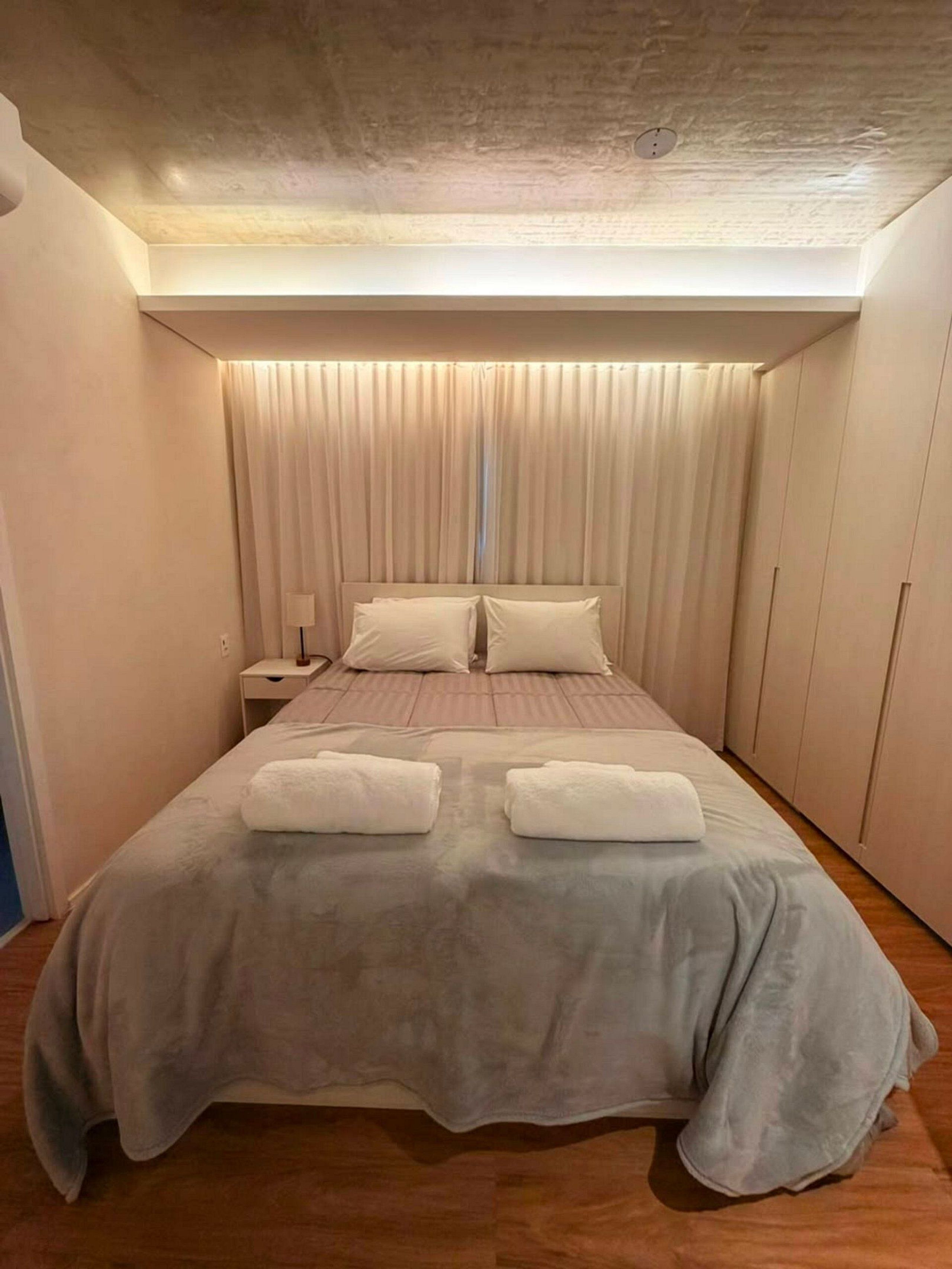 Ein Schlafzimmer mit einem Bett, Kissen, einem Nachttisch und einer Nachttischlampe.