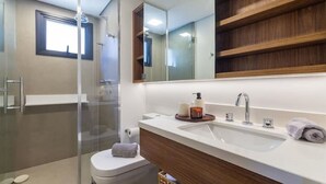 A modern bathroom with a glass shower enclosure, a white sink with a wooden vanity, and a large mirror above the vanity. - Arte Itaim (São Paulo)