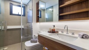 A modern bathroom with a glass shower enclosure, a white sink with a wooden vanity, and a large mirror above the vanity. - Arte Itaim (São Paulo)
