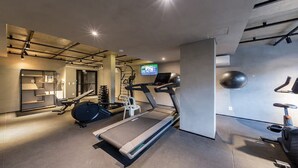 A modern gym with treadmills, weight machines, and a television screen. - Arte Itaim (São Paulo)