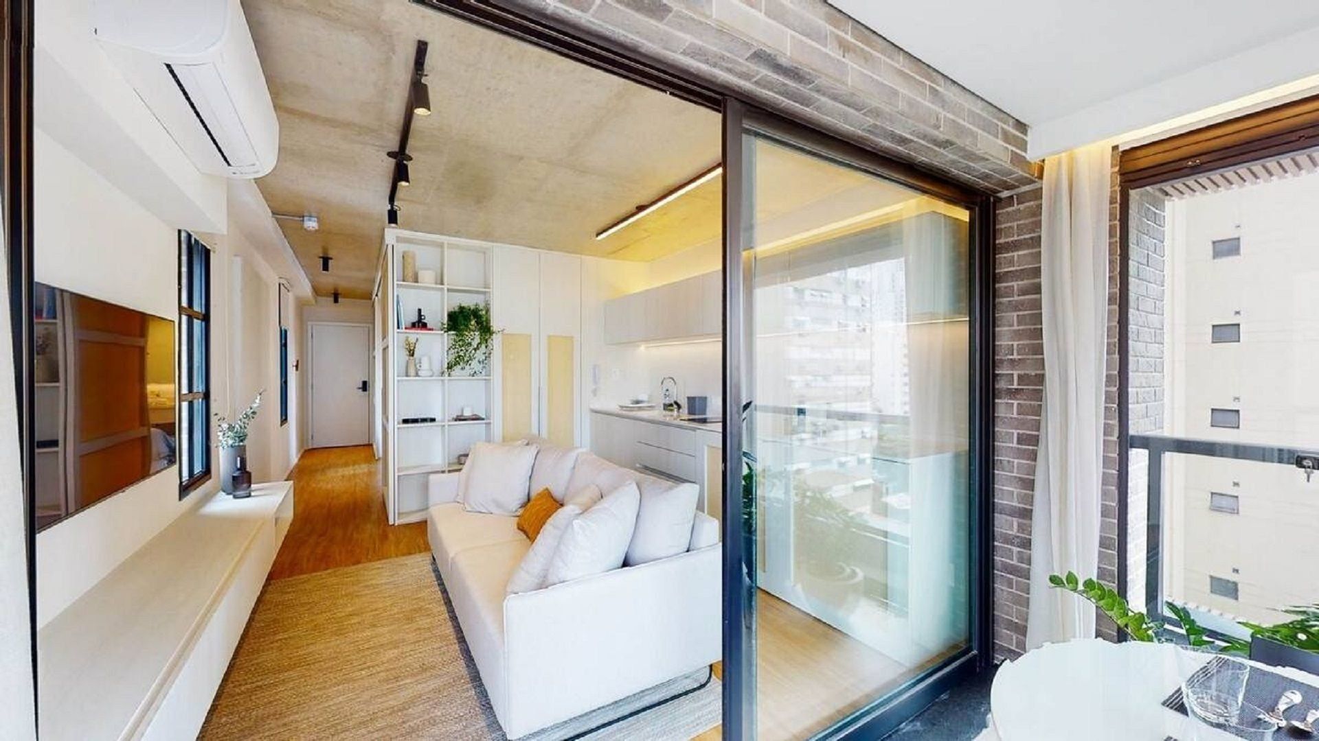 Een modern interieur met een witte bank, een keukenhoek en een groot raam.