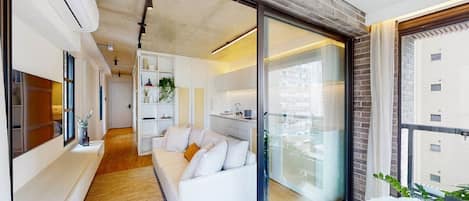 A modern interior with a white sofa, a kitchen area, and a large window.