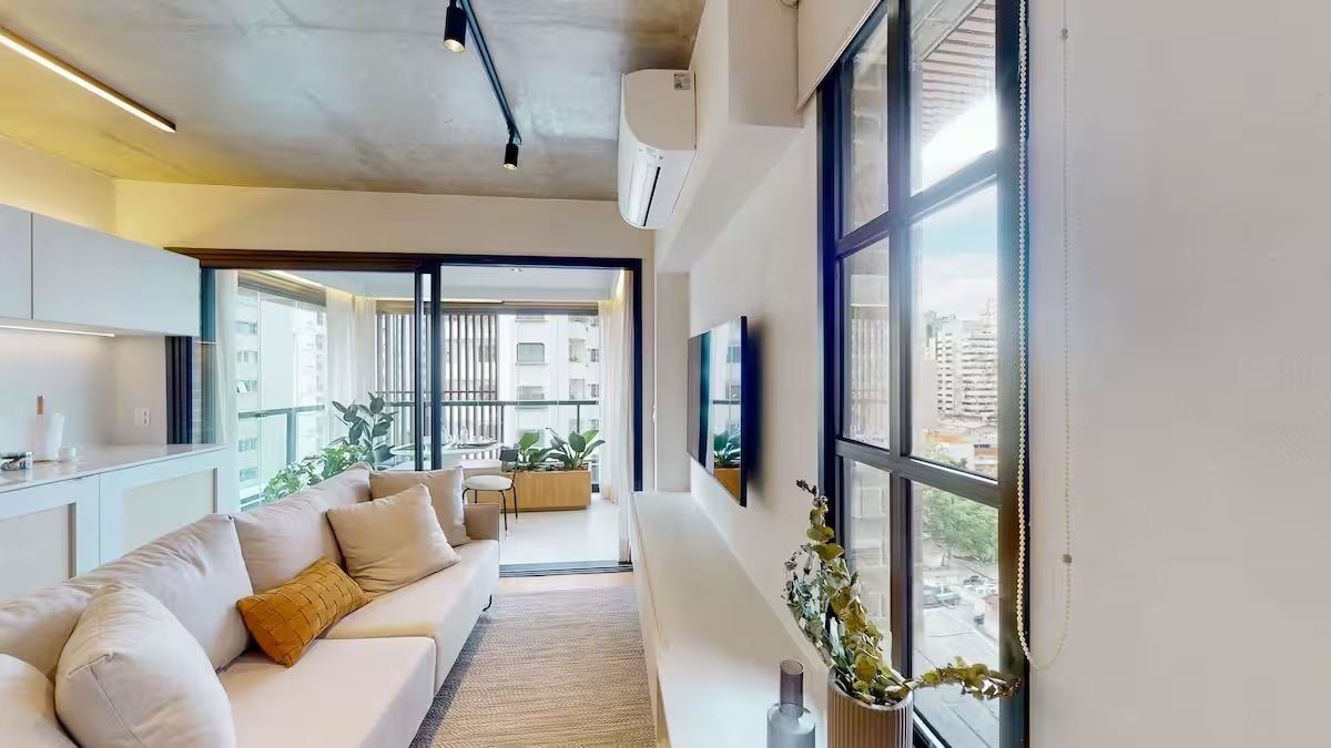Uma sala de estar moderna com sofá, televisão de tela plana e uma grande janela com vista para edifícios.