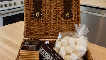 Un panier de pique-nique en osier avec une anse, contenant une tablette de chocolat au lait Hershey's, des guimauves et une autre tablette de chocolat.