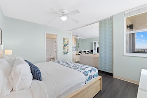 Ein Schlafzimmer mit Bett, Deckenventilator, Fenster mit Aussicht und einer Küchenzeile.