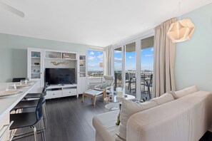 Ein modernes Wohnzimmer mit Fernseher, Sofa, Esstisch und Stühlen.