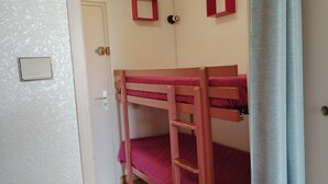 Ein Stockbett mit einer Leiter, einer Tür und einem Lichtschalter an der Wand.
