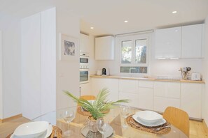 A modern kitchen with white cabinets, a built-in oven, and a window.