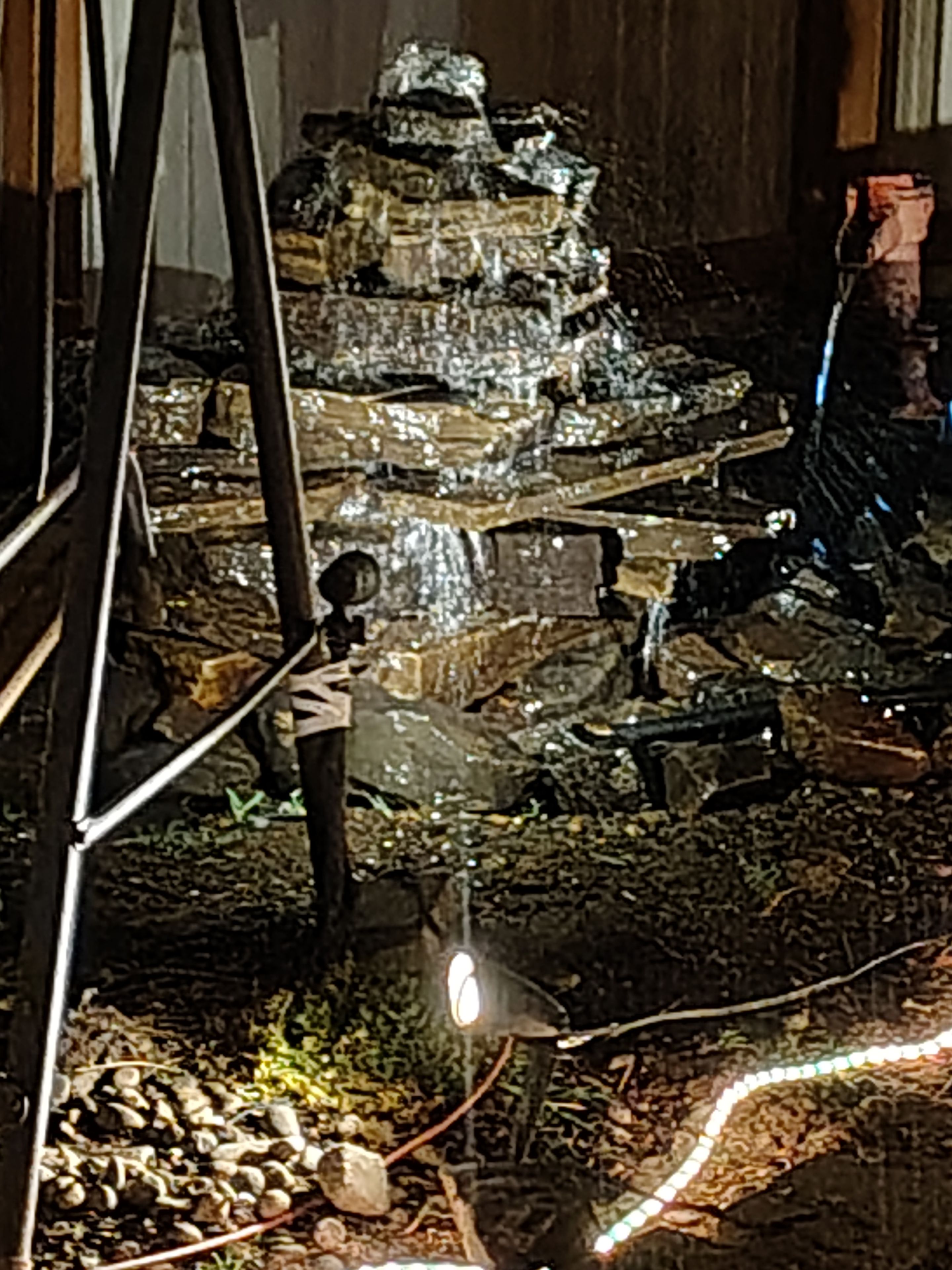 Ein Wasserbecken aus Stein mit einem stufenartigen Design, umgeben von Steinen und Moos.