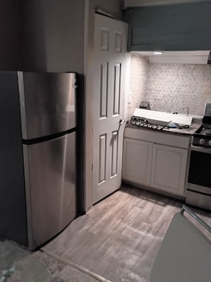 A kitchen with a stainless steel refrigerator, a white door, a stove, and white cabinets. - Tranquil 1-bedroom house with AC in welcoming Salem (Salem)