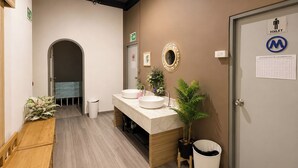 A modern bathroom with a wooden bench, two sinks, a mirror, and a potted plant. - Blue Dream Hostel Khaosan (Bangkok)