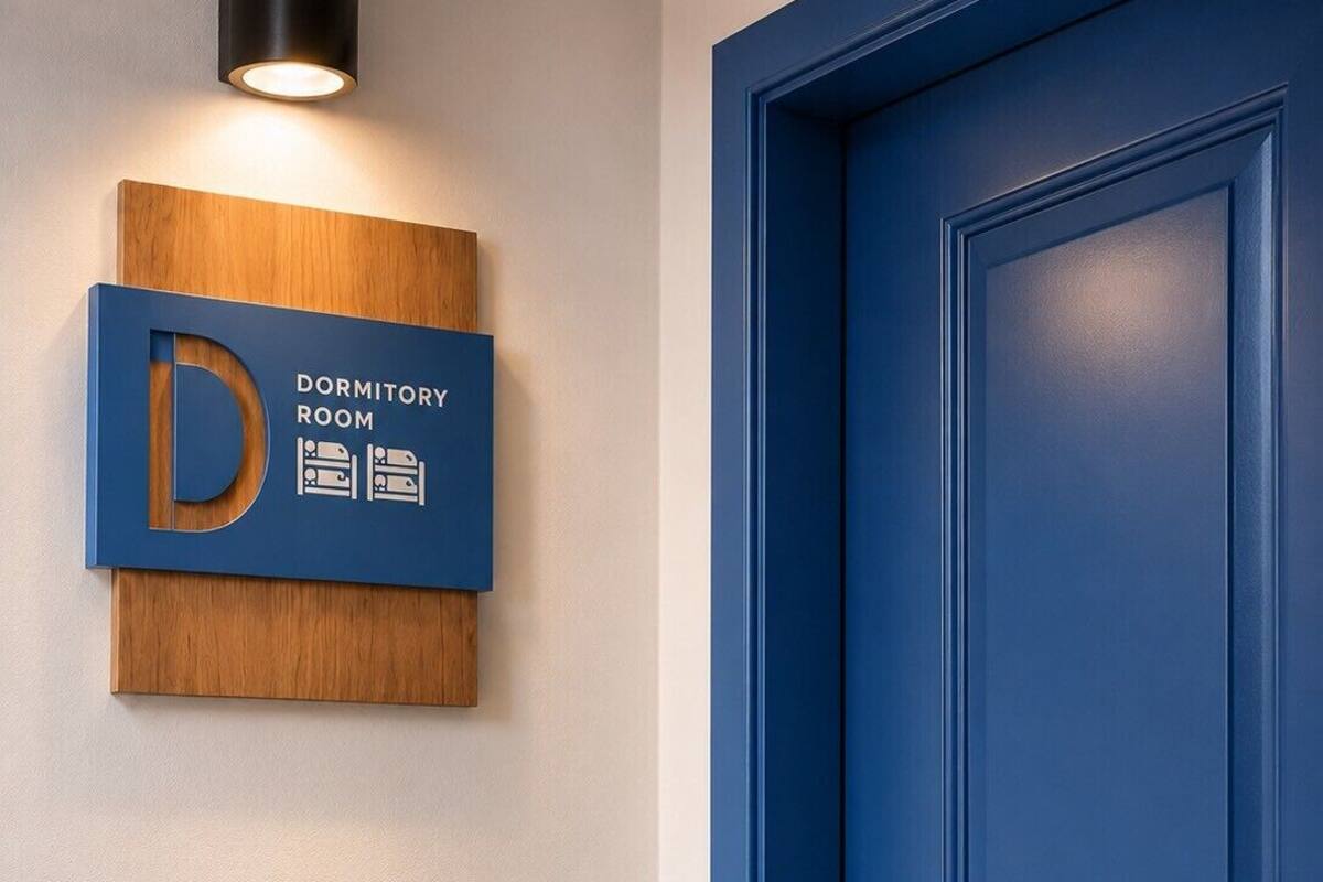Une porte bleue avec une pancarte au-dessus indiquant qu’il s’agit d’une chambre de dortoir.