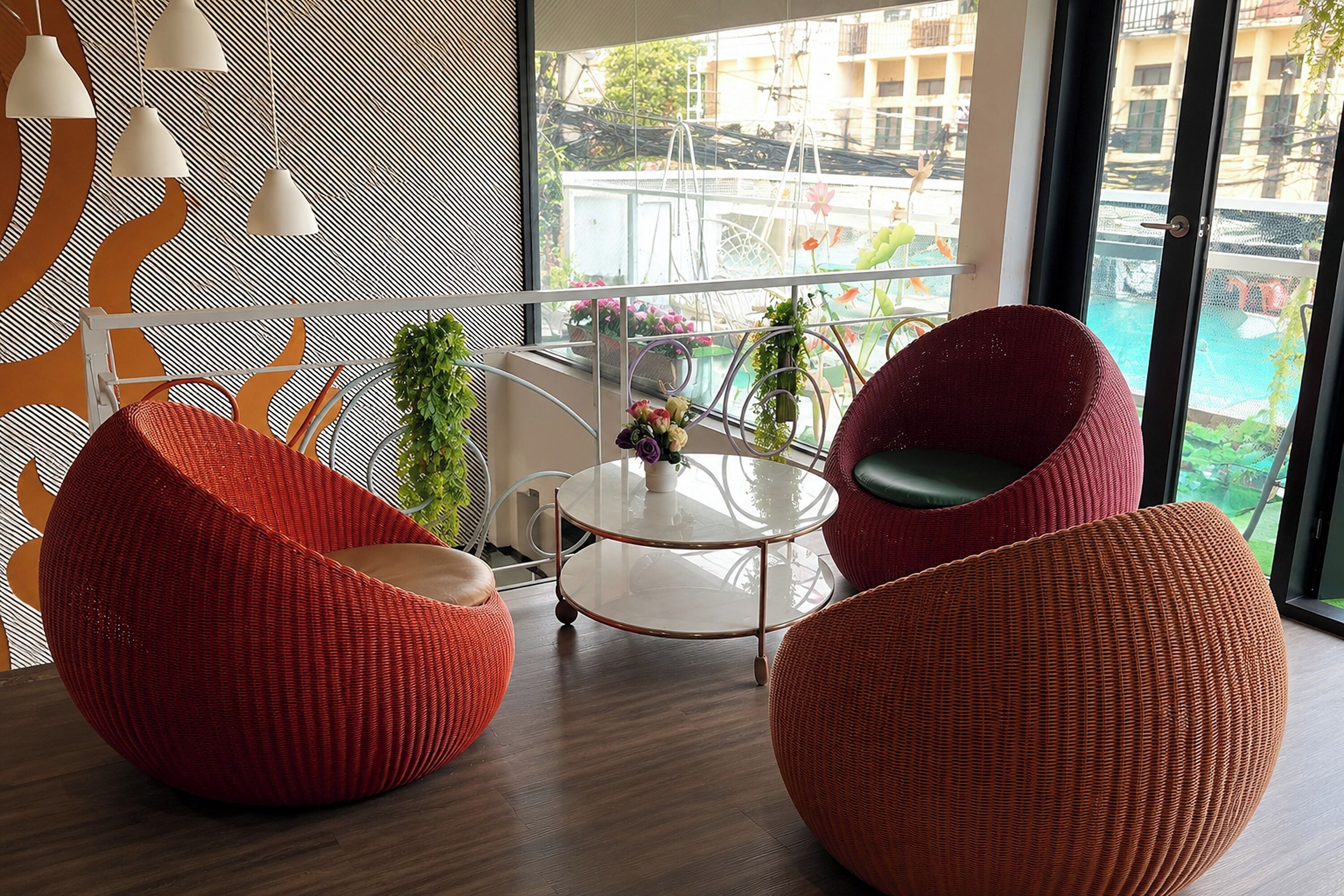 A modern interior with two red woven chairs, a glass table, and a view of a pool through large windows.