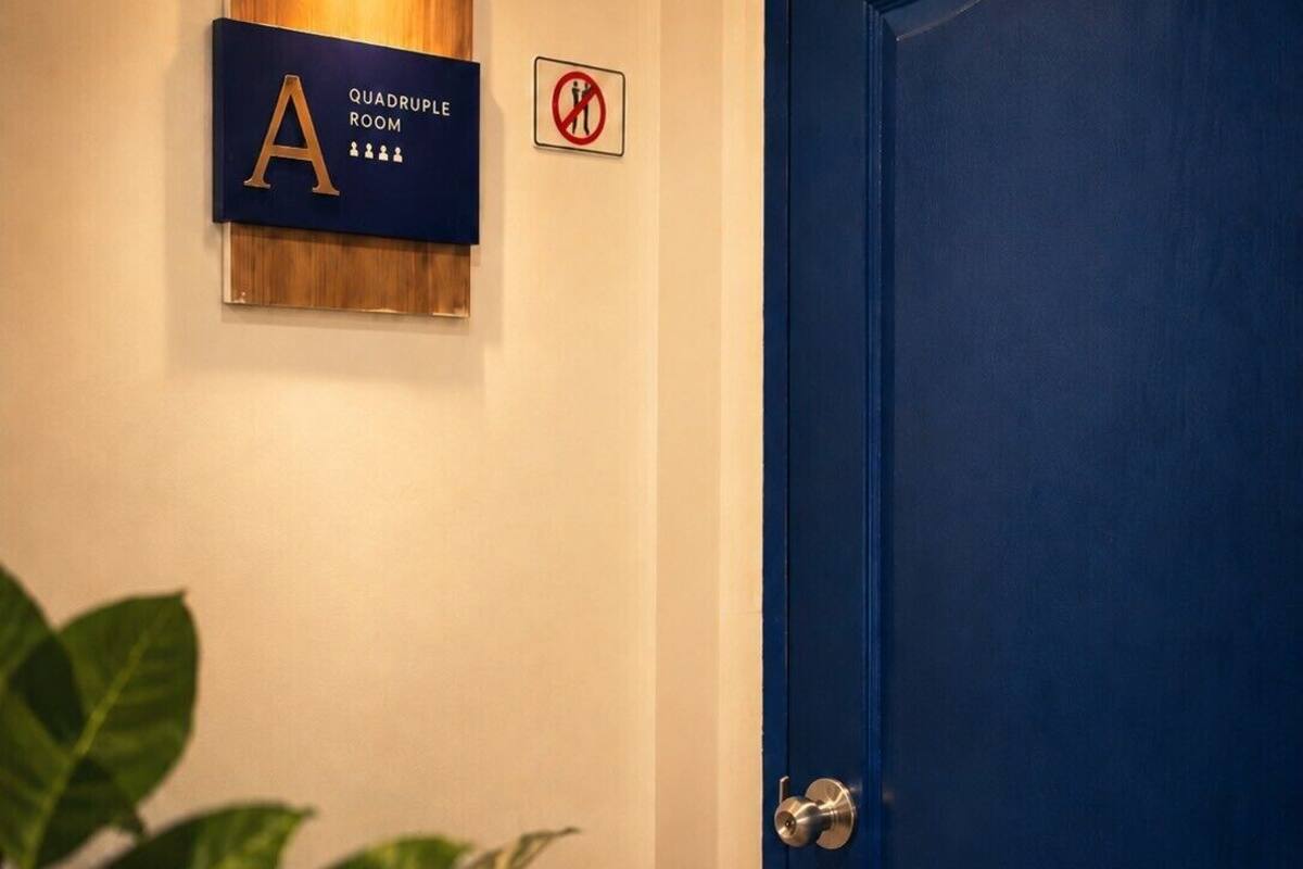 Une porte bleue, un panneau indiquant une salle équipée d’un quadripôle, et un panneau interdisant de fumer.