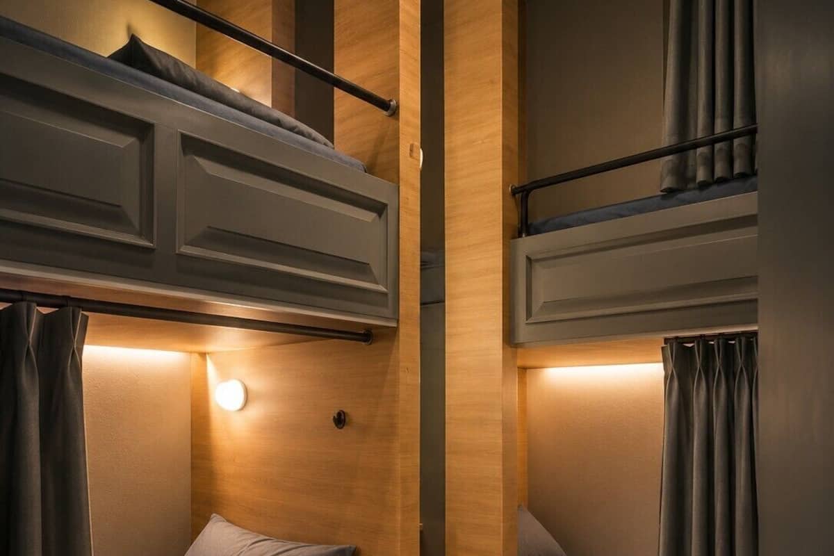 Une petite pièce avec des lits superposés, une petite étagère et une porte.