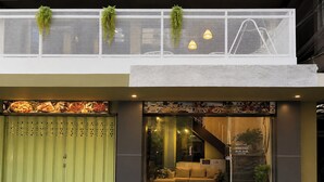 A hotel entrance with a green door, a staircase, and a seating area inside. - Blue Dream Hostel Khaosan (Bangkok)