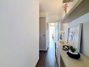Ein Flur mit hellem Boden, einem Empfangsschalter mit Blumenvase und einem gerahmten Bild an der Wand.
