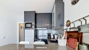 A modern kitchen with a granite countertop, stainless steel appliances, and a built-in oven. - MEDA CHICA Roses / Roses - INTERimmo (Rosas / Roses)