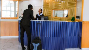 A reception desk with a blue and wooden design, a Dell computer, and a plant.