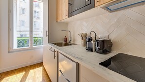 Een moderne keuken met een inbouwoven, een spoelbak en een raam met uitzicht op een gebouw.