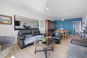 Un salon moderne comprenant un canapé, des fauteuils, une table basse et un coin repas avec une table et des chaises.