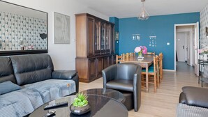 Un salon moderne comprenant un canapé, une table à manger avec des chaises, un meuble et un lustre.