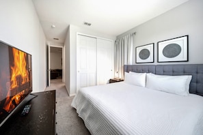 Enjoy a cozy bedroom adorned in soft gray tones and plush textiles, creating a serene retreat. The stylish decor and sleek furniture blend perfectly, while natural light fills the room, enhancing its inviting warmth. - 9BR house with private pool at Solara Resort (Kissimmee)