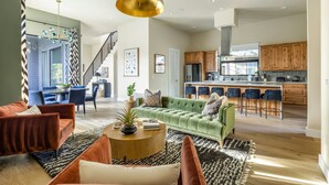 A spacious living room with a green sofa, a round coffee table, and a staircase leading to an upper level. - Skyline in Hyde ~Two Rooftop Terraces~ Pool+Spa (Austin)