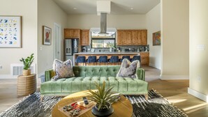 A modern living room with a green sofa, a coffee table, and a kitchen in the background. - Skyline in Hyde ~Two Rooftop Terraces~ Pool+Spa (Austin)