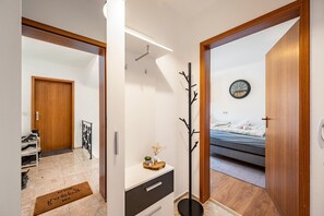 Une chambre à coucher comprenant un lit, une table de chevet, une horloge murale et une porte donnant sur une autre pièce.